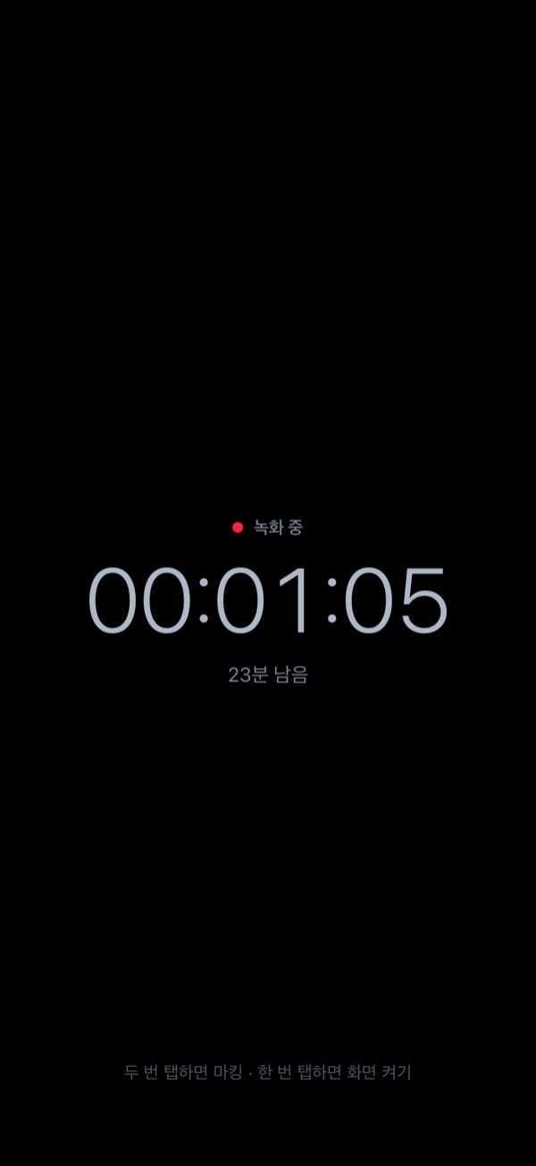 Dimmed recording screen in Korean. A black background shows only the recording indicator, elapsed time, and time left, with a hint below: double tap to mark, single tap to wake the screen.